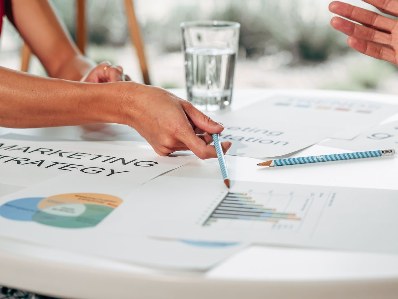Services-01 Ruce probírající marketingovou strategii s grafy v kancelářském prostředí.